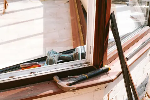 Drill and hammer on a window sill during a repair.