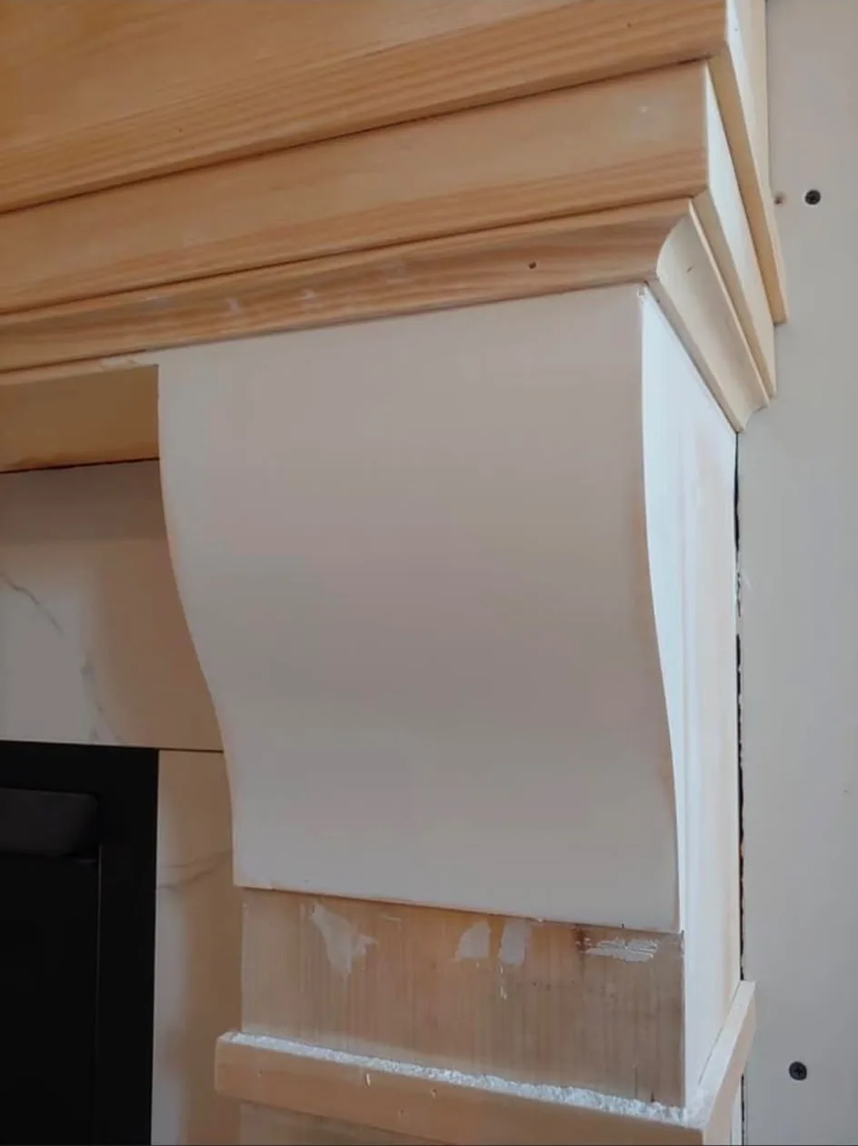 Bespoke chimney breast being built, with a curved hood, bare pine mouldings and marble-effect tiling to the surround.