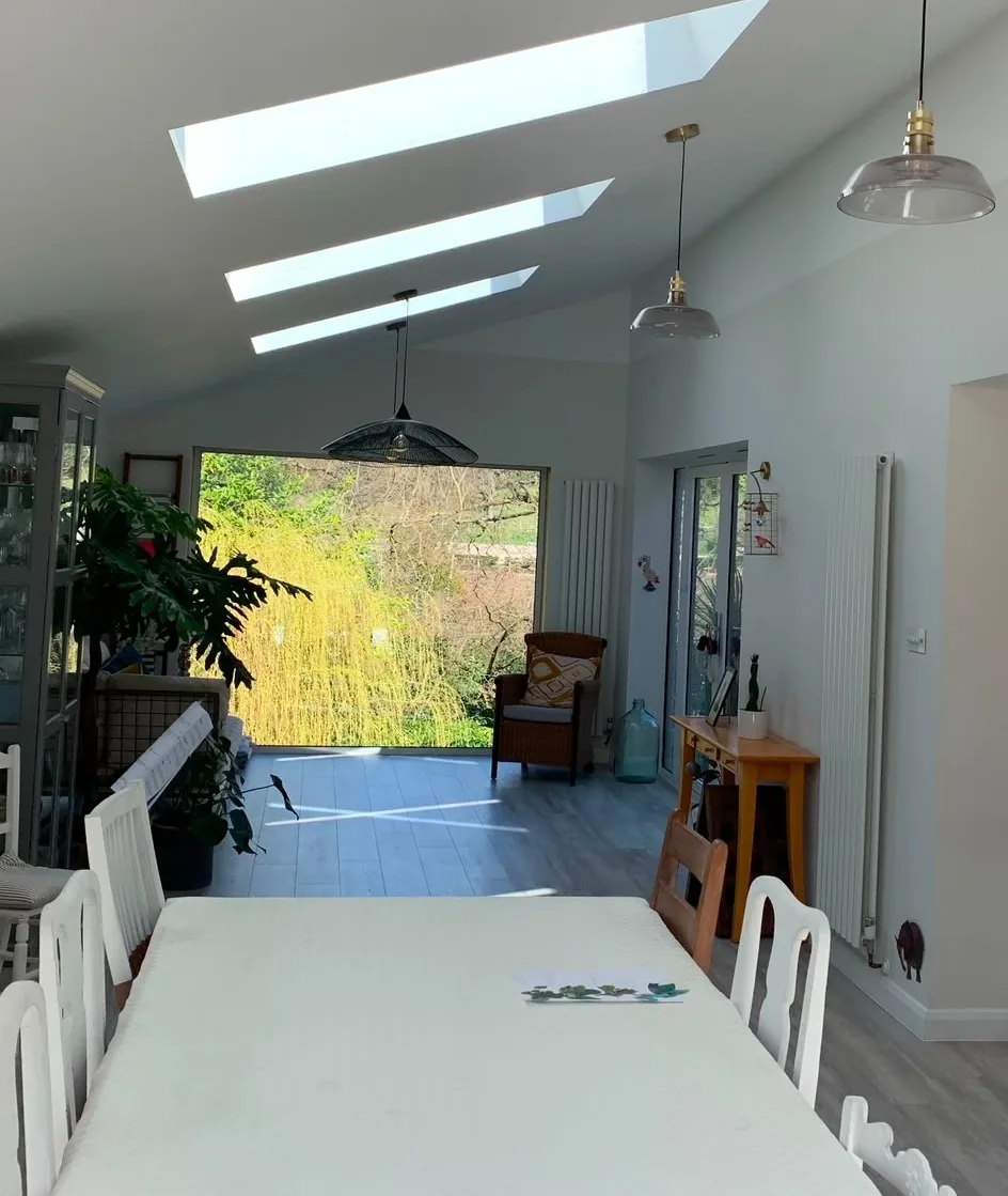 A vaulted dining room in a rear extension with three narrow roof lights and sliding doors opening onto the garden.