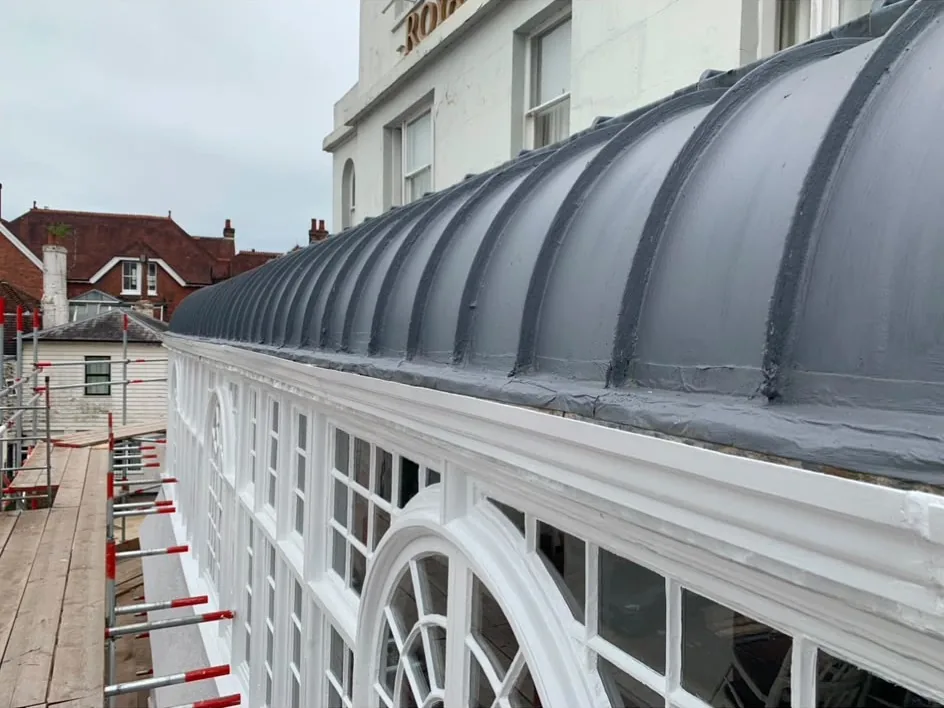 New lead barrel roof laid over a curved glazed veranda, with the white painted timber glazing and arched fanlights finished underneath.