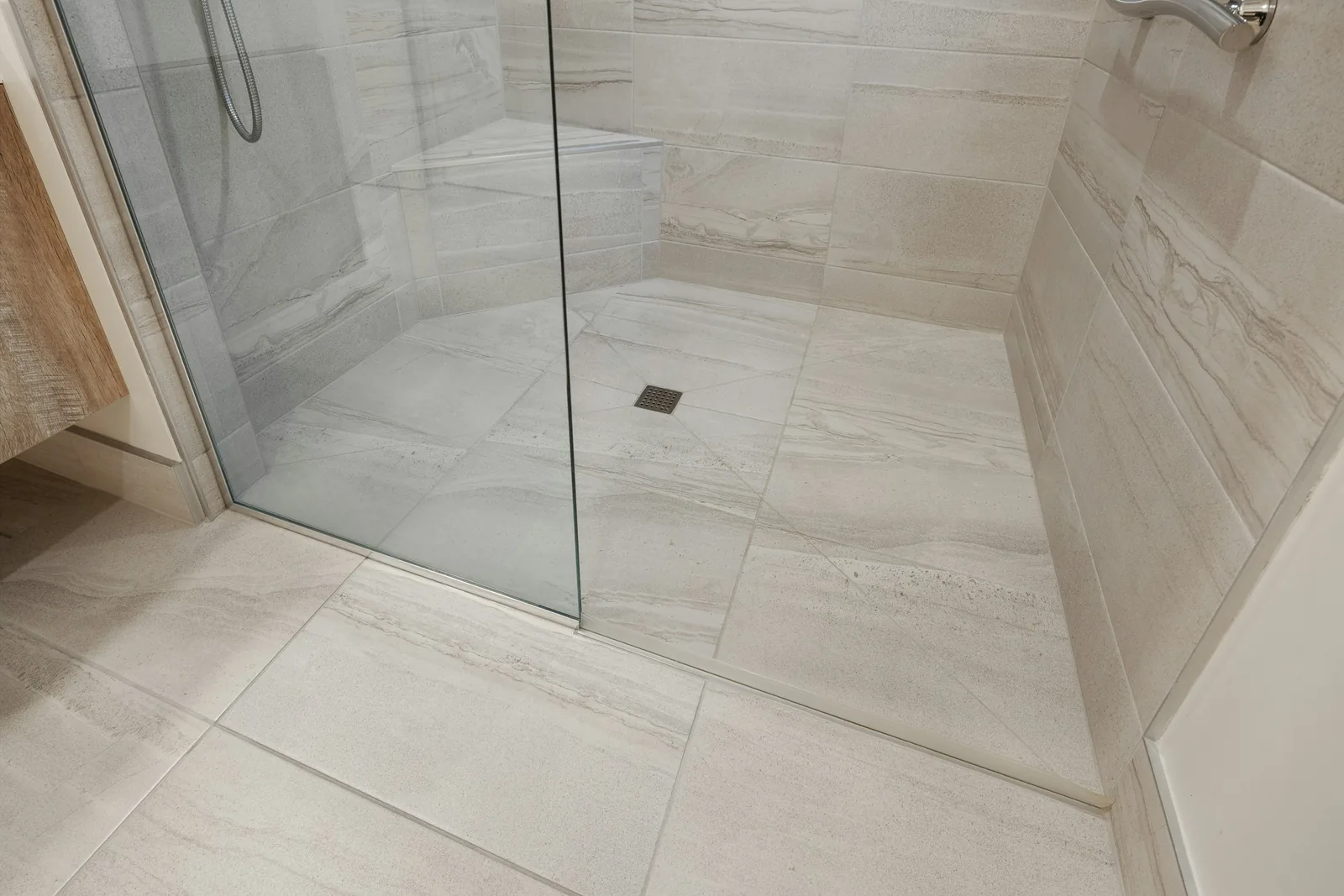 Pale tiling carries on under a glass screen to a square gully set into the shower floor.