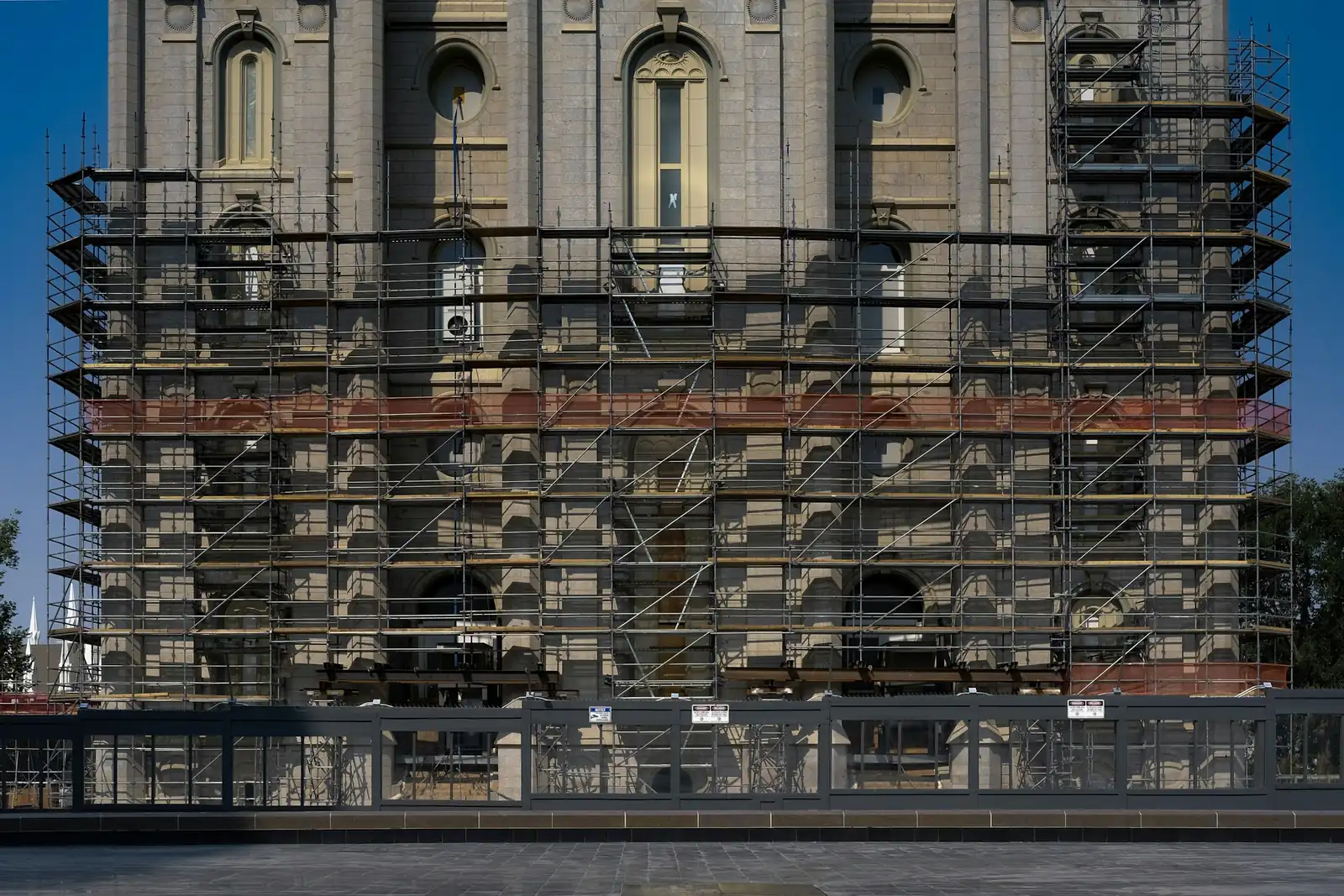 Scaffold reaches well up a stone elevation but stops below the tall arched windows above.