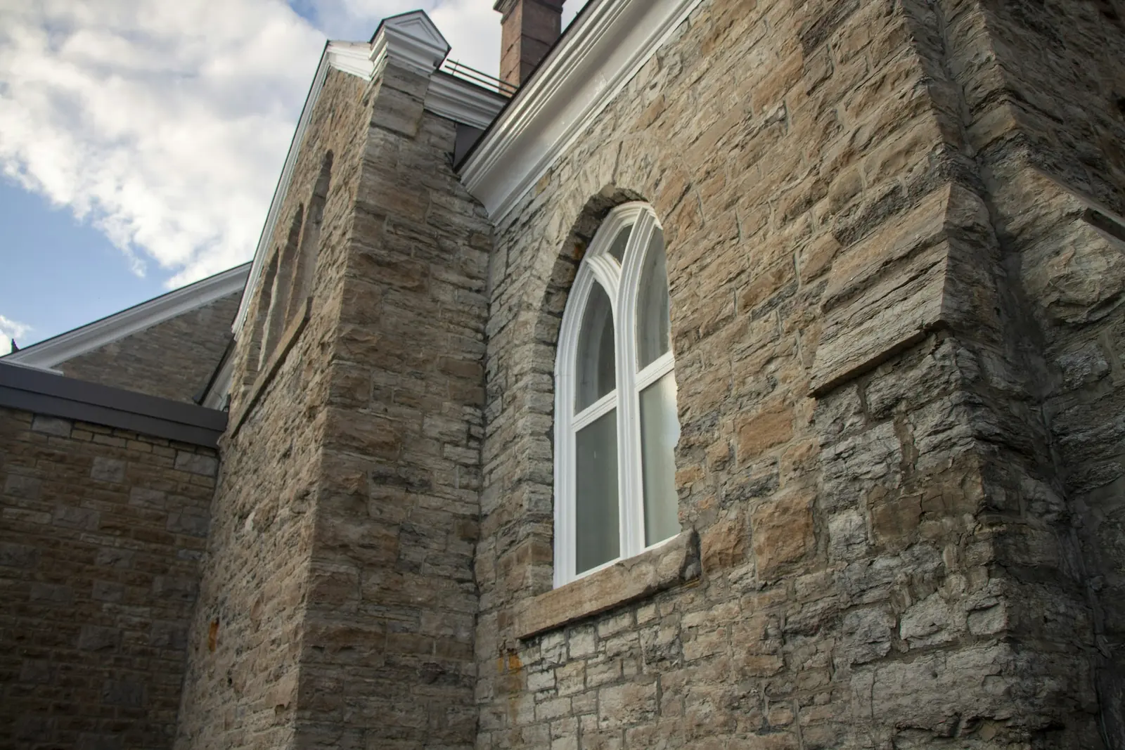 The stone wall and arched window of a historic building.