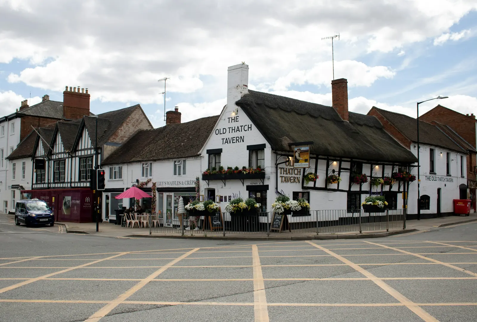 The thatched corner pub is painted white, and so is the chimney stack above its gable.