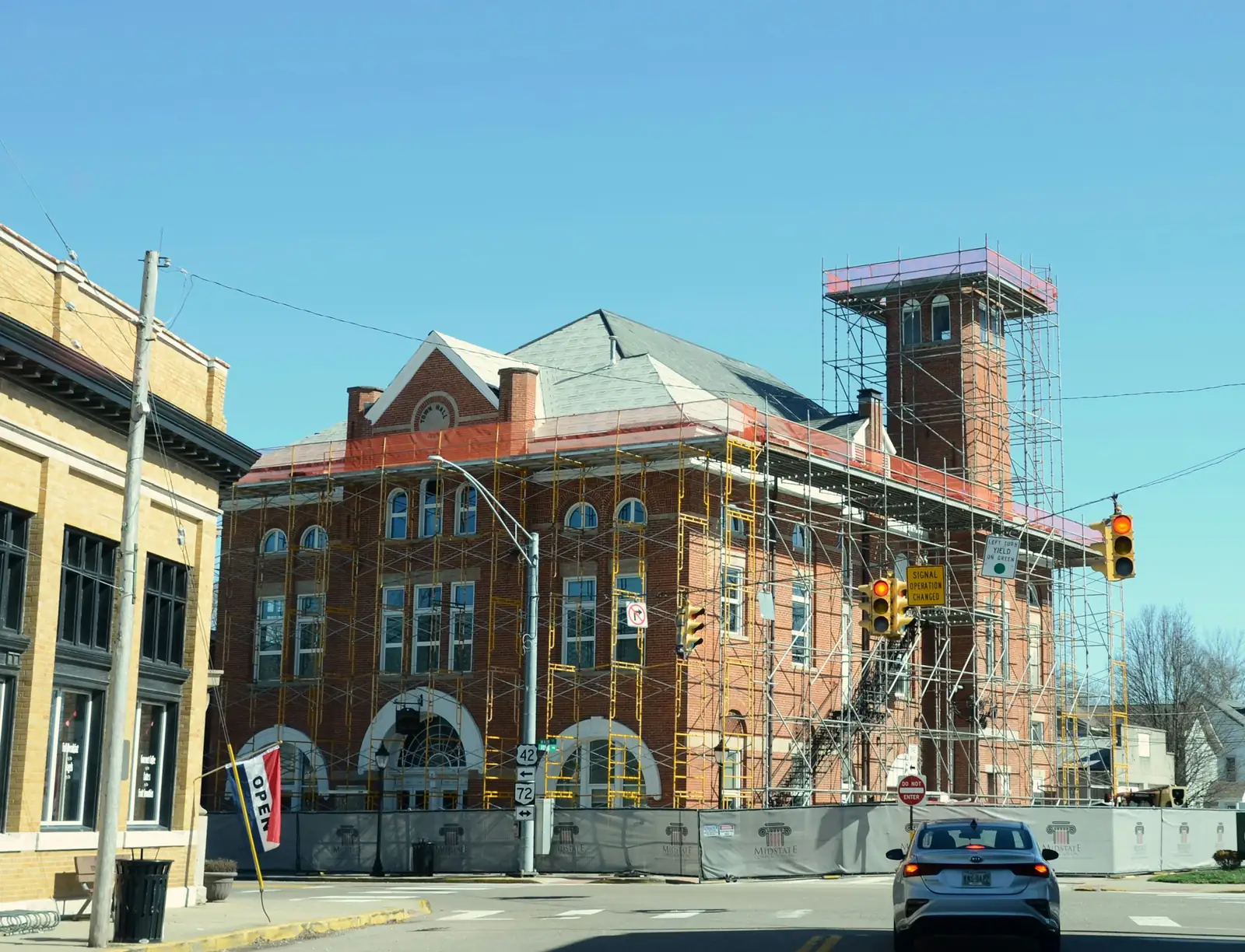 Scaffold boxes in the tower of a red brick town hall and runs along the front.