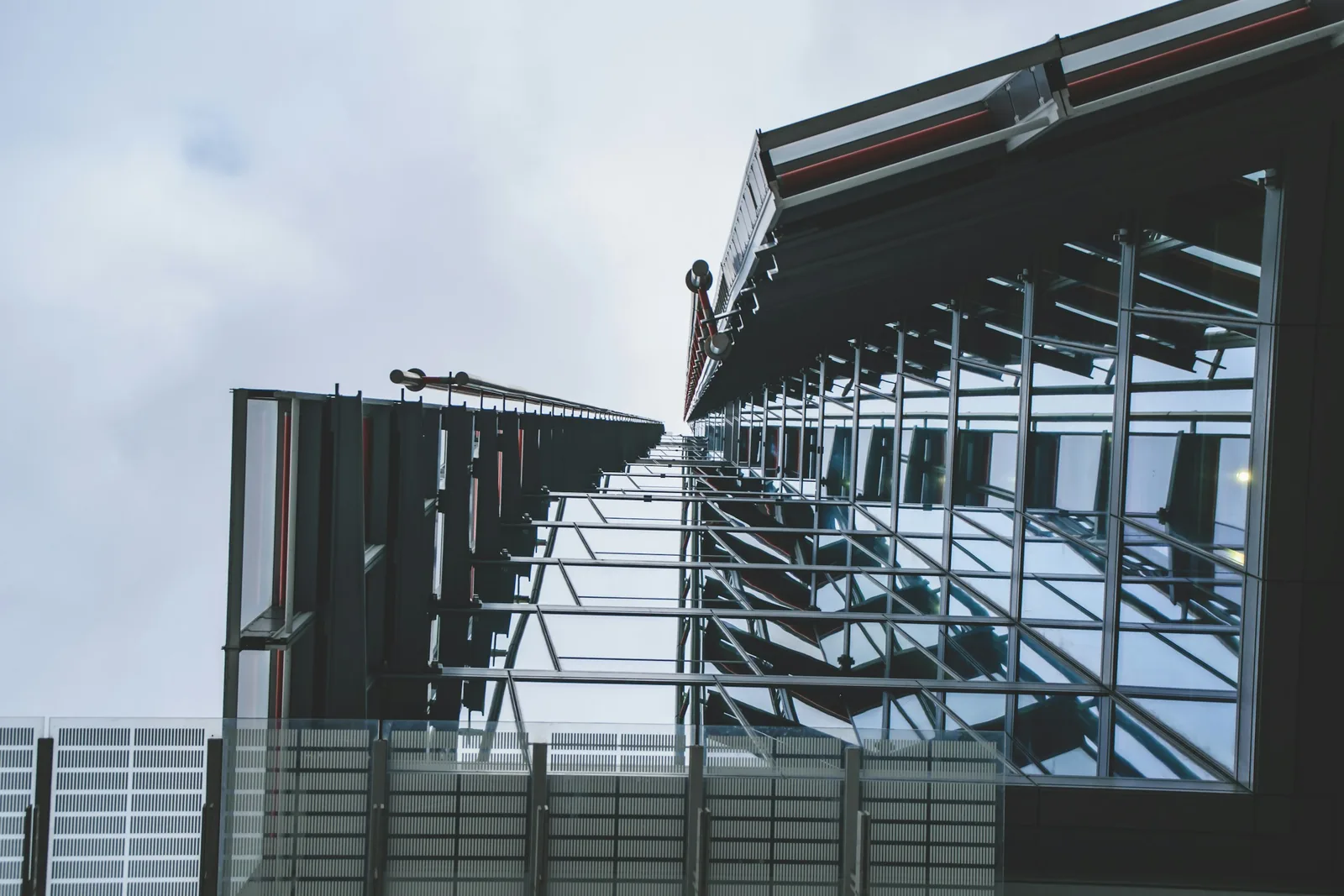 Rows of glass louvres hang off steel arms along the glazed elevation.