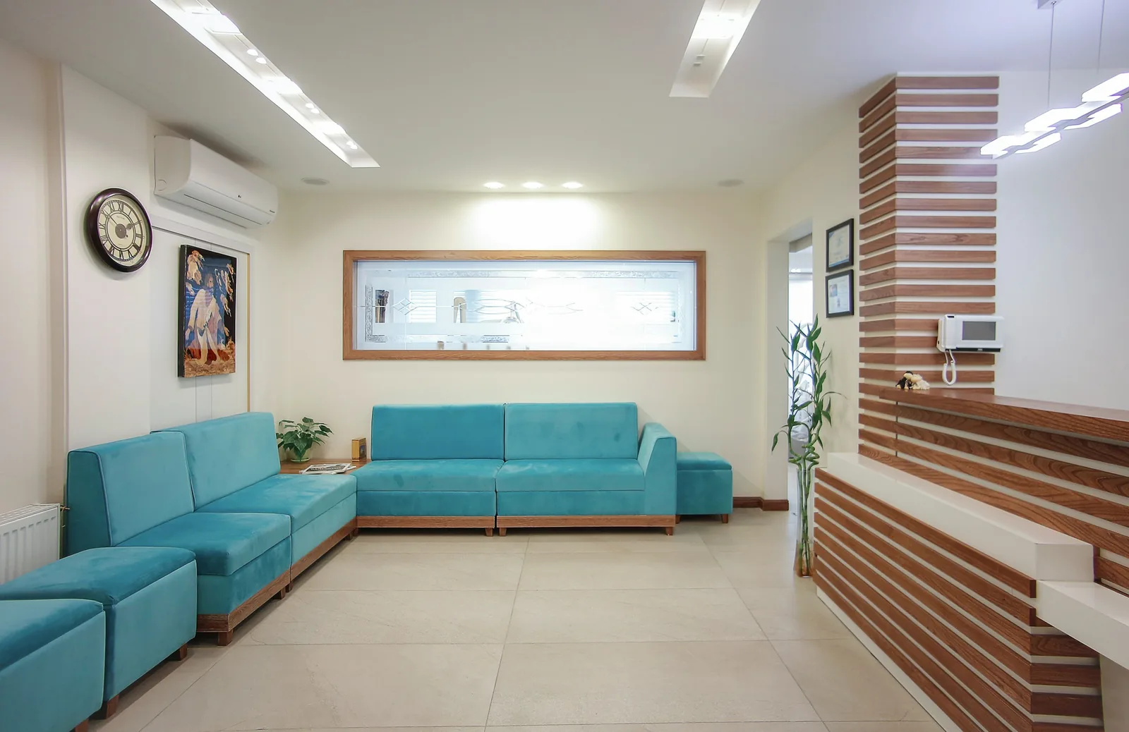 Timber slats clad the reception desk and wall, with turquoise modular sofas along two sides.