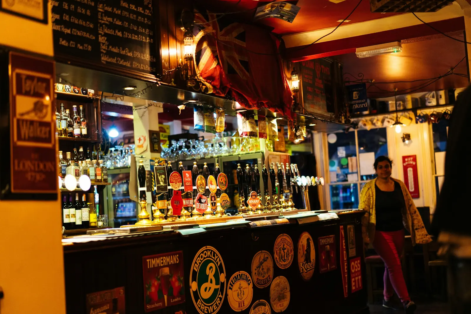 Brewery clips label a bank of hand pumps, and round plaques cover the bar front.