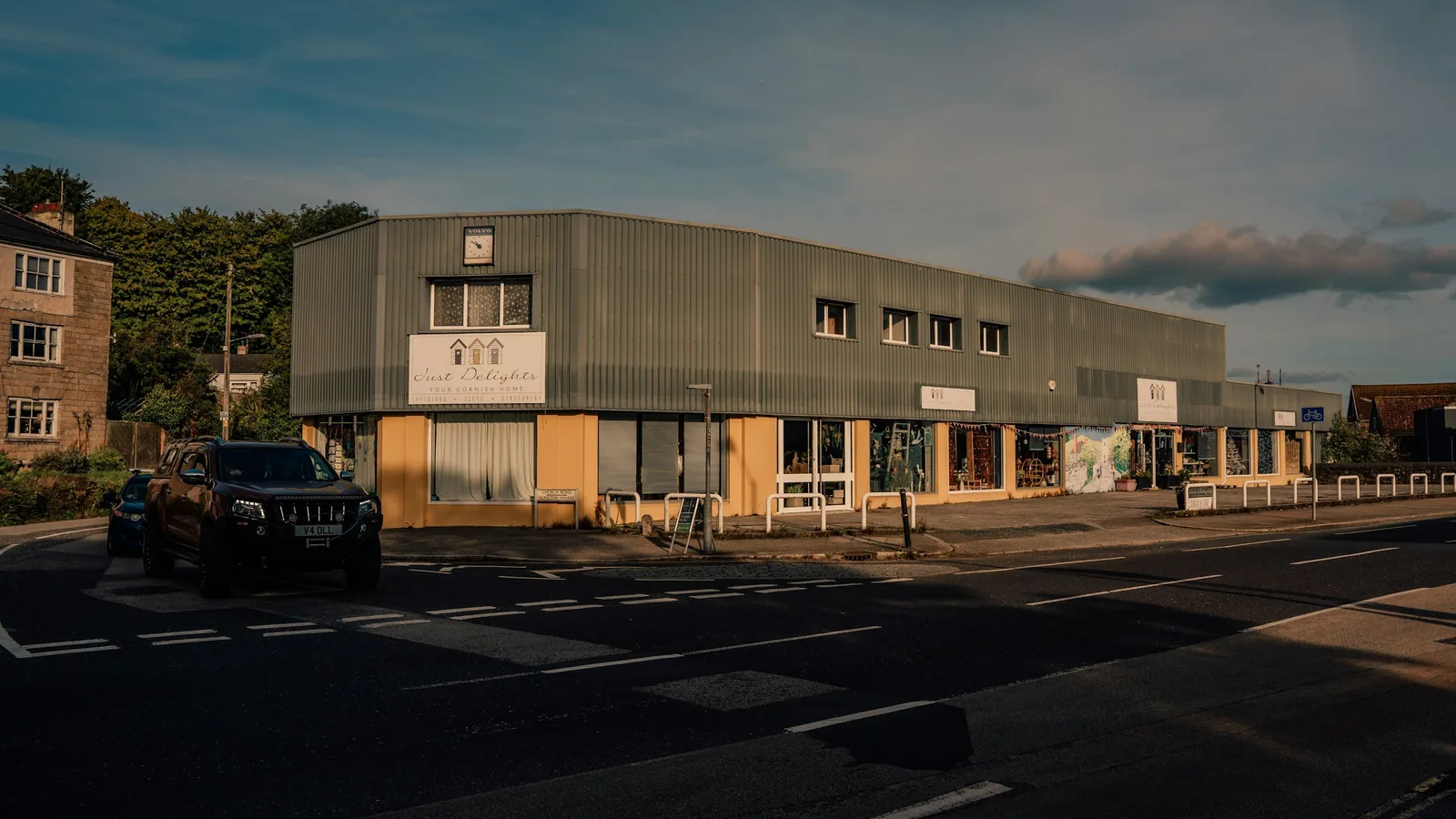 A grey-clad two-storey commercial unit with a row of windows, beside a road in Cornwall.