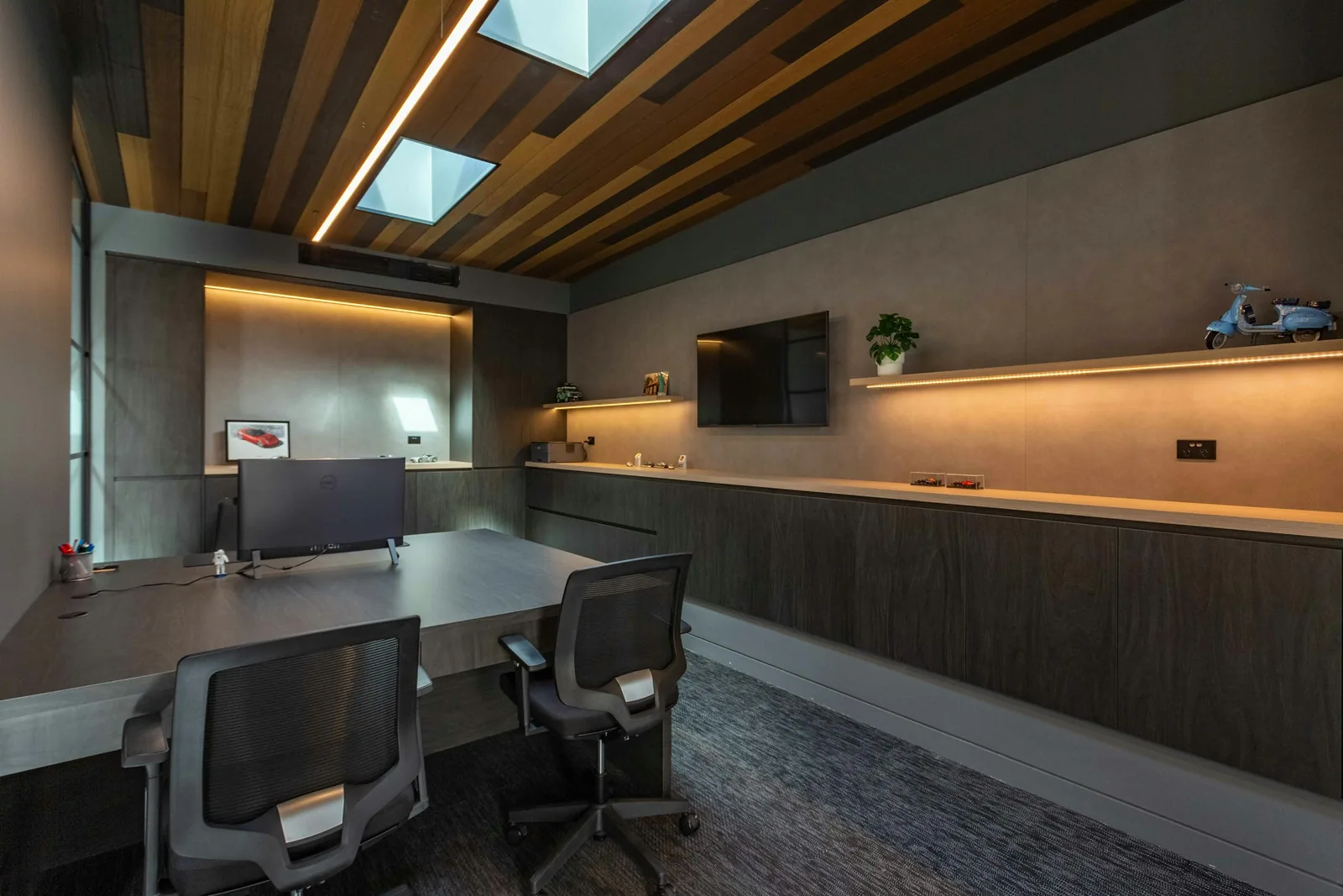 The ceiling is boarded in mixed timber and cut for two square rooflights above a dark veneer wall.