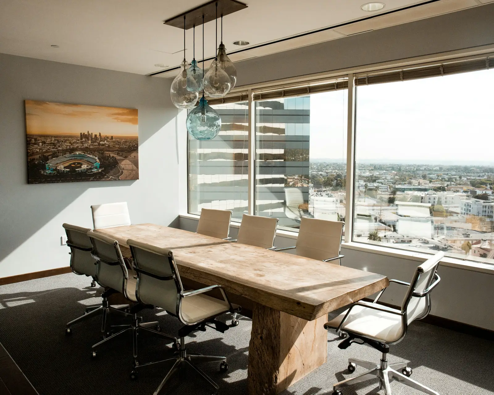 A rough timber slab on a block base makes the boardroom table, with blue and clear pendants above.