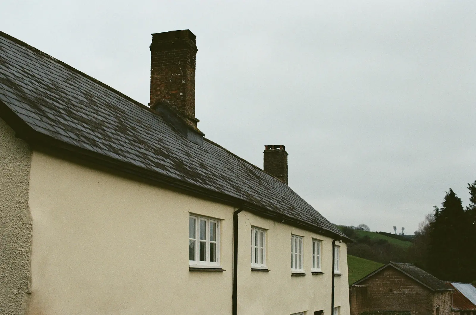 A rendered house with a dark tiled roof and chimneys.