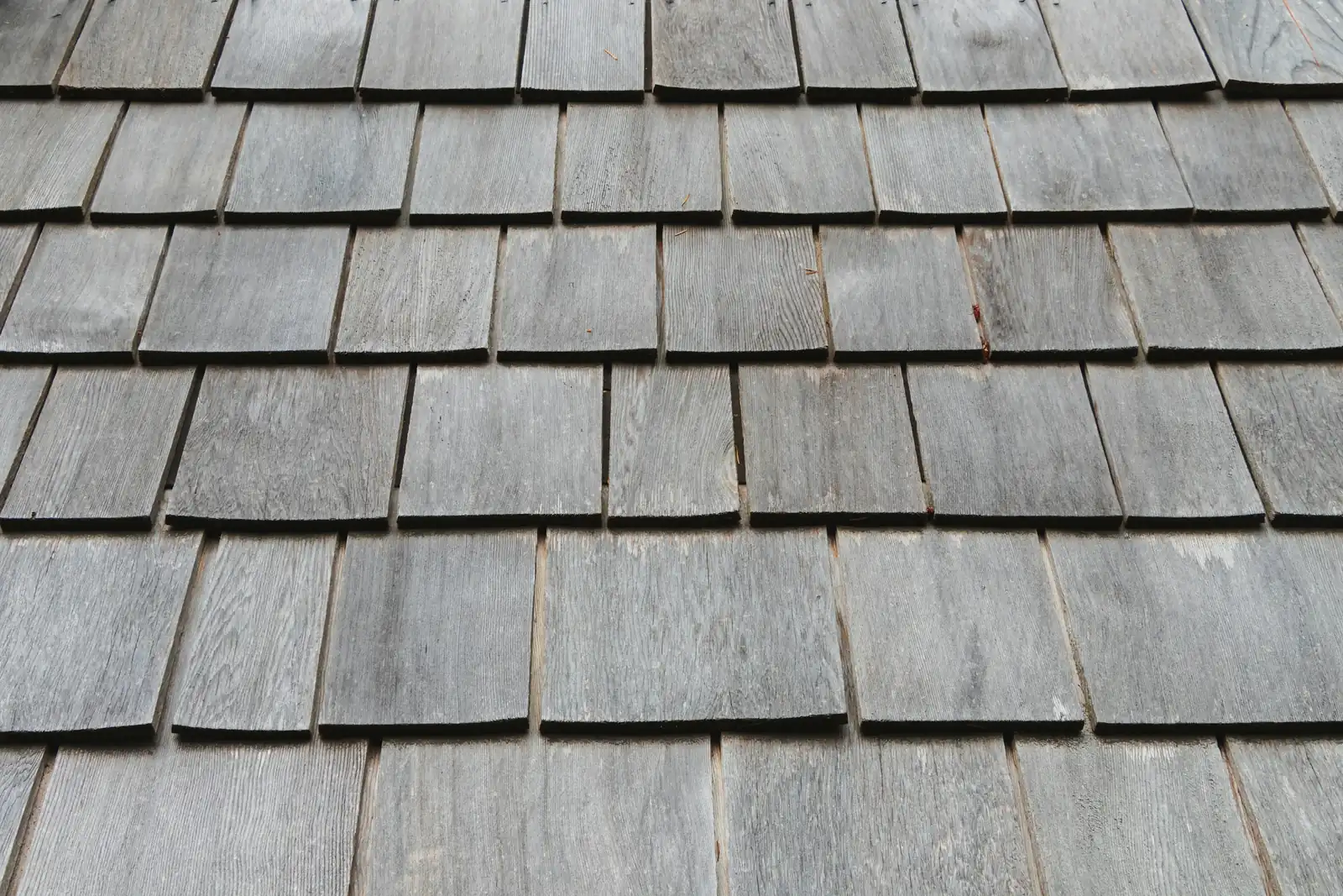 Each course of sawn timber shingles laps the one below it, all weathered to grey.