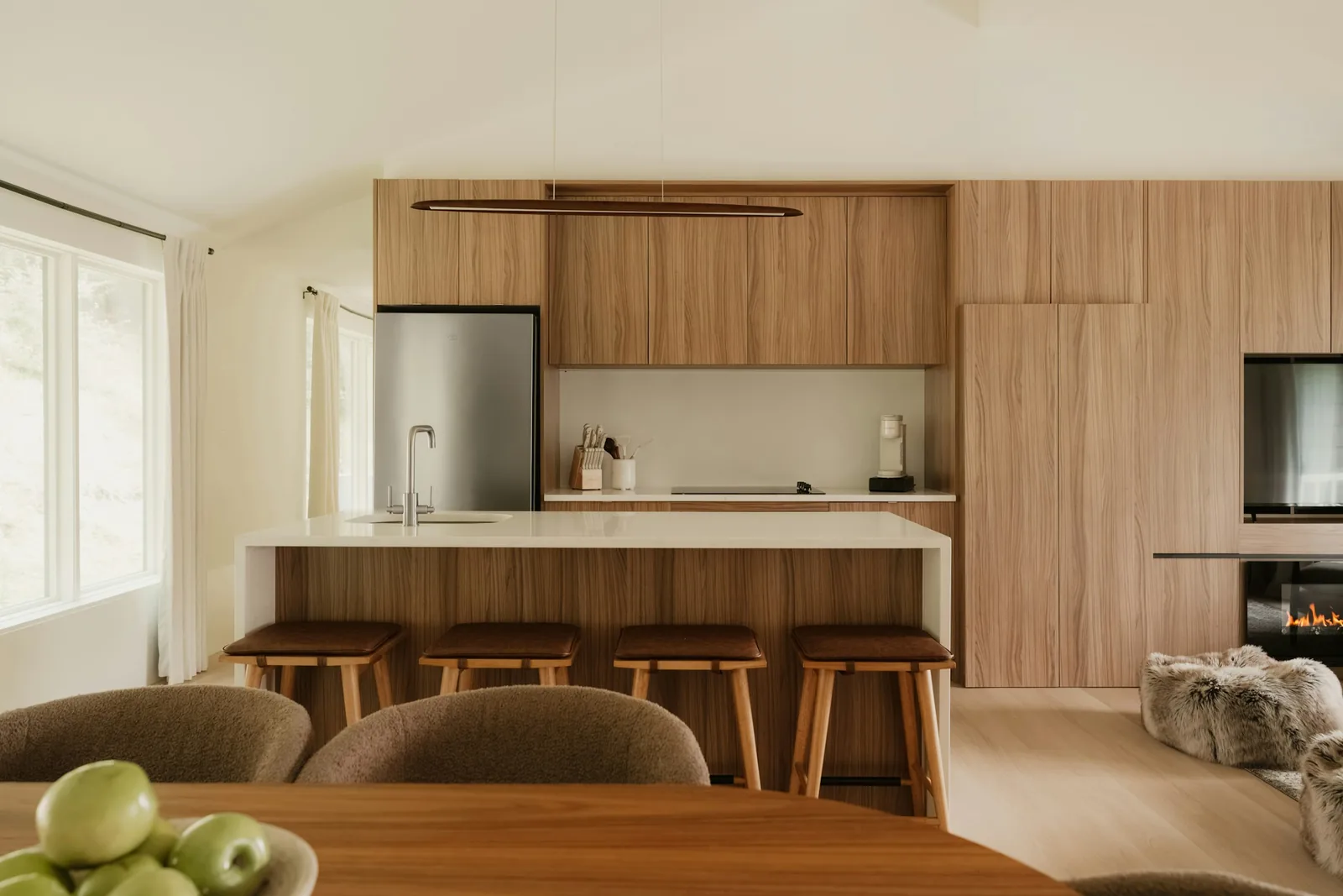A kitchen with wood cabinets, a white island and stools.