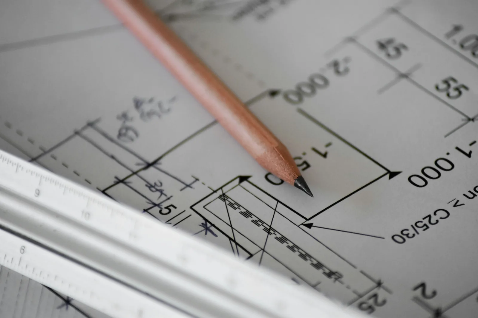 A pencil resting on a dimensioned architectural drawing.