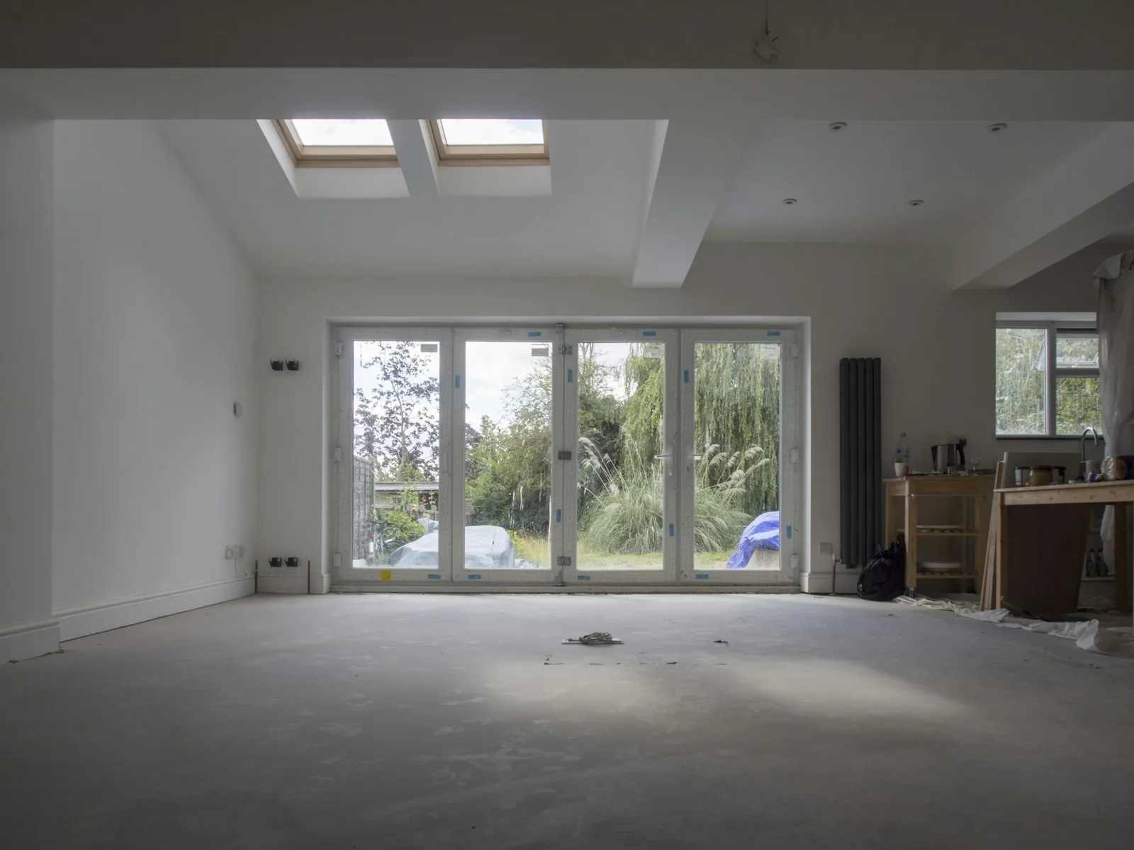 Bare screed underfoot and blue transport tape still on the new garden doors.