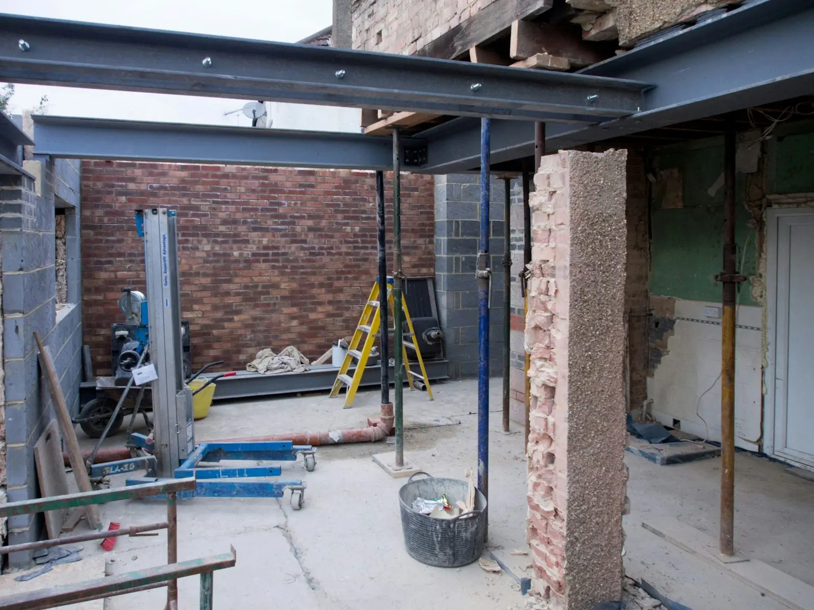 Bolted steel beams sit on acrow props where the back wall has been opened up.