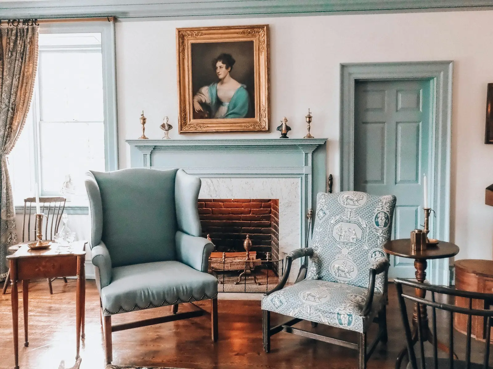 A period drawing room with a marble fireplace, panelled walls and upholstered chairs.