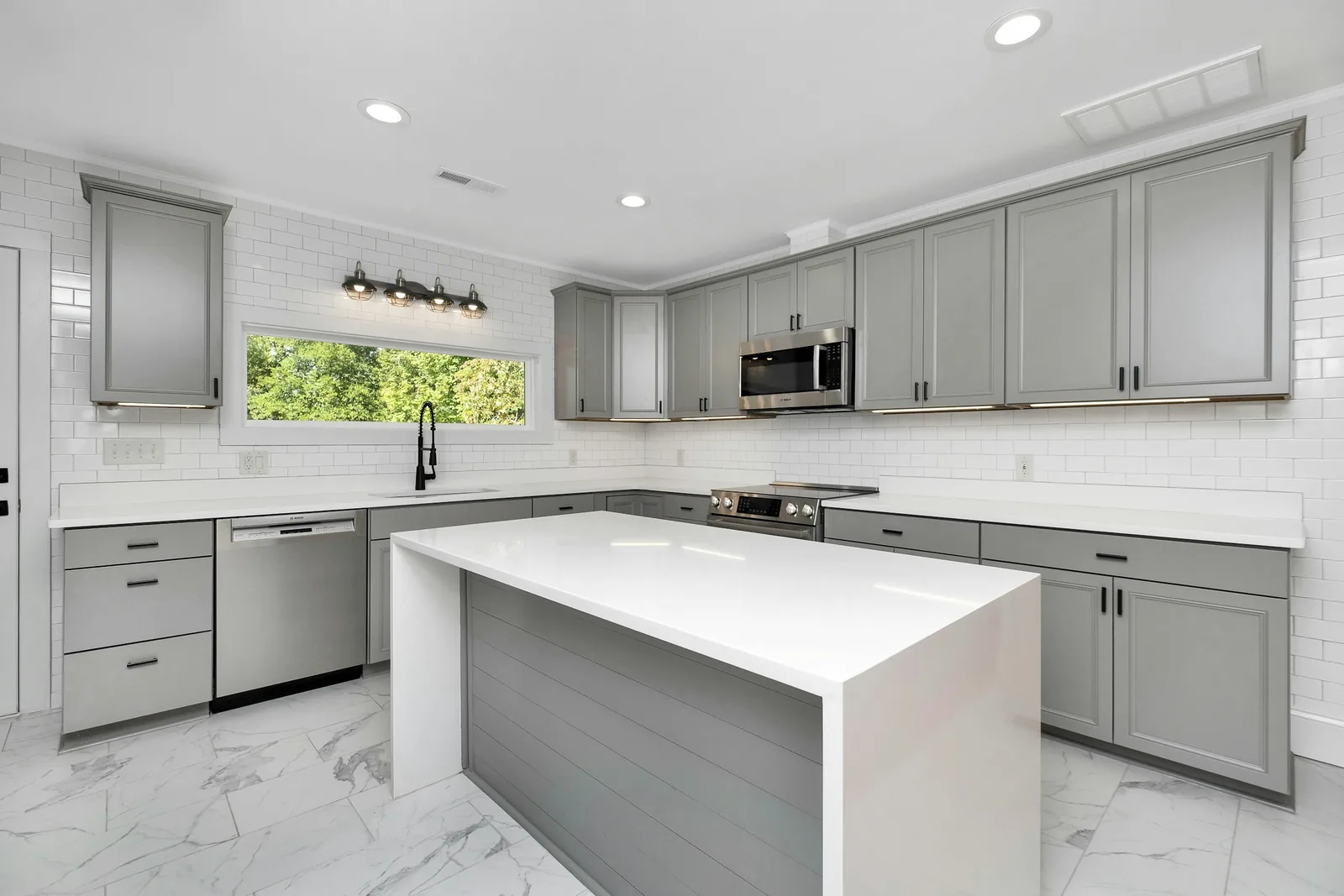 A plain white fitted kitchen with an island and worktop.