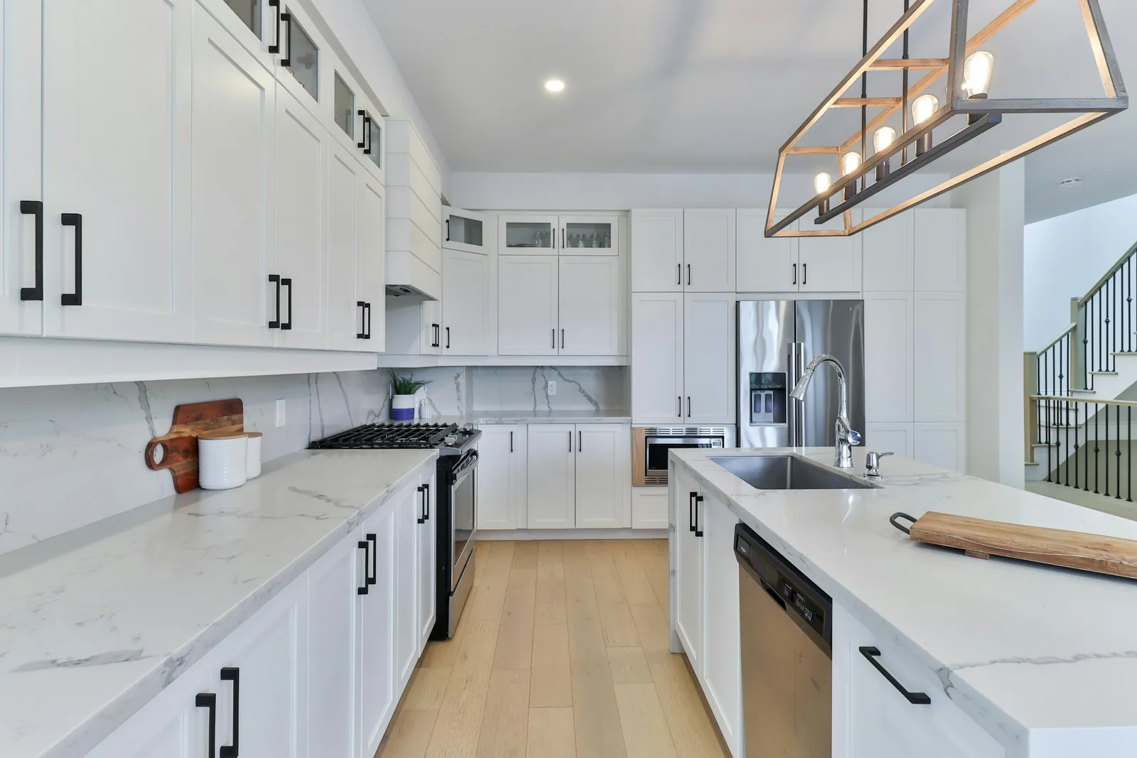 A white fitted kitchen on a wooden floor.