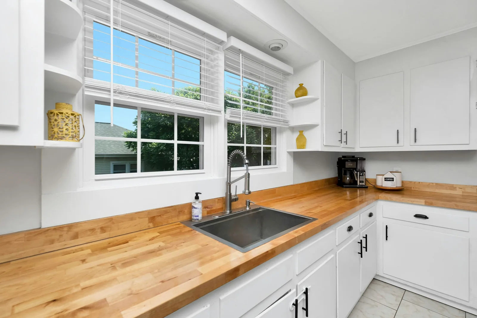 An oak worktop and white shaker units beside a kitchen window.