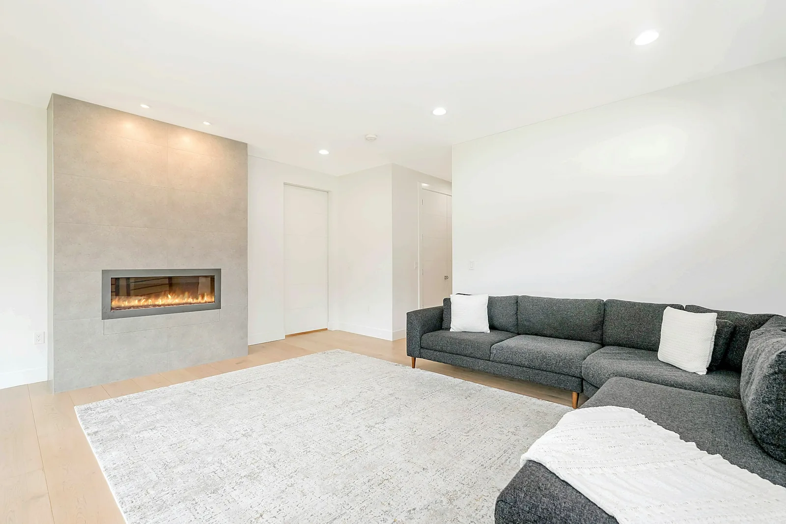 A plain living room with a sofa beside a fireplace.