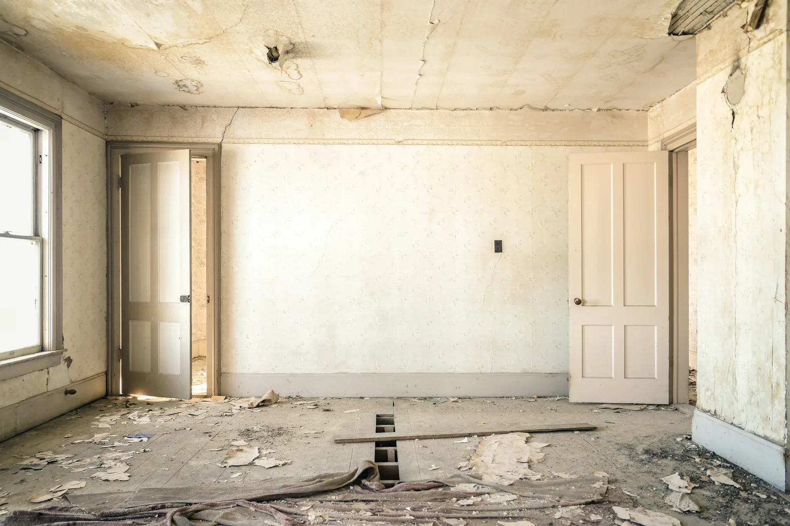 An empty room stripped back to bare plaster and floorboards during refurbishment.